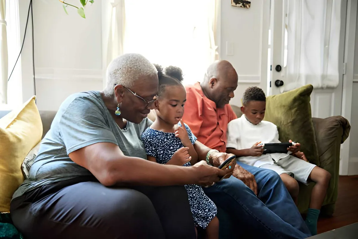Grandparents and two children sharing phones and tablets on a sofa
